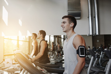 man with smartphone exercising on treadmill in gym