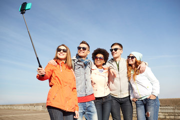 smiling friends taking selfie with smartphone