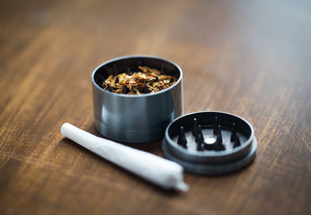close up of marijuana joint and herb grinder - obrazy, fototapety, plakaty