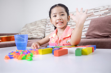 Portrait of cute asian little girl playing brick on table at hom