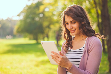 Close up of happy woman using tablet in park