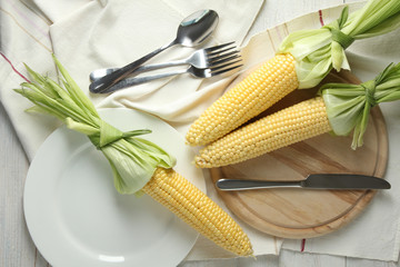 corn on wooden cutting board with tableware