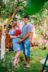 Fototapeta premium young happy beautiful couple in love walking together on grass and trees park landscape on sunset in summer with man holding his wife with pregnant belly in family concept