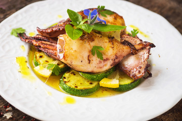 Grilled squid with lemon and zucchini on wooden background