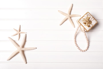 Fototapeta na wymiar Summer concept: Idea with starfish and pearl necklace on white wooden with space for text.