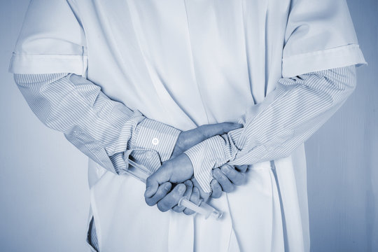 Doctor hide behind syringe on back ,holding in  hands. Medical concept.