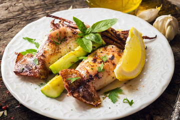 Grilled squid with lemon and zucchini on wooden background
