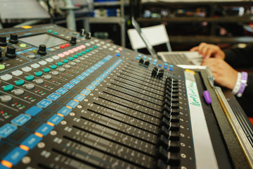 Black professional mixer with buttons and sliders to control the audio output power amplifier speakers.