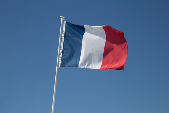 French flag is waving in the wind, on the blue sky