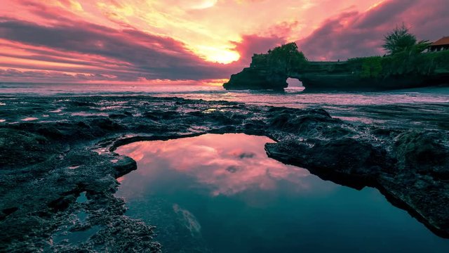 Sunset at sea beach made of rocks with holes filled by seawater in Batu Bolong temple. 4K Timelapse - Bali, Indonesia, June 2016.