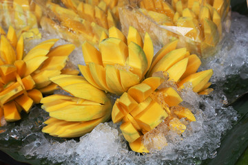 peel and chop mangoes on the ice at the market for sell
