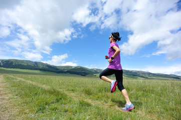 healthy lifestyle young woman runner running on beautiful trail in grassland