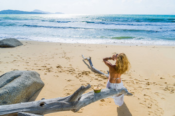 Woman sitting on a tree at the beach