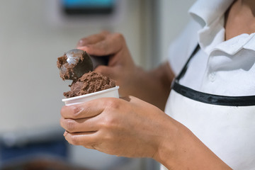 saleswoman in an ice cream parlor takes a scoop of ice cream
