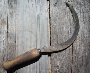 Old sickle on the wooden table