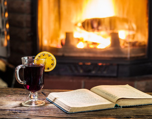 Hot mulled wine and a book on the wooden table.