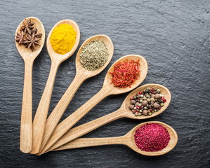 Assortment of colorful spices in the wooden spoons.