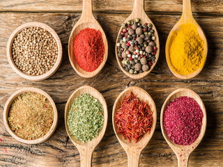 Assortment of colorful spices in the wooden spoons.