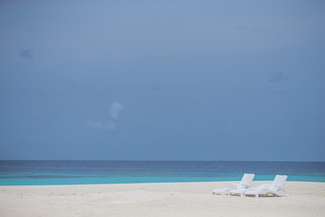 Fototapeta na wymiar three beach chairs on the white beach