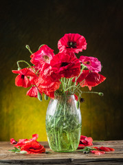 Bouquet of poppy flowers in the vase on the wooden table.