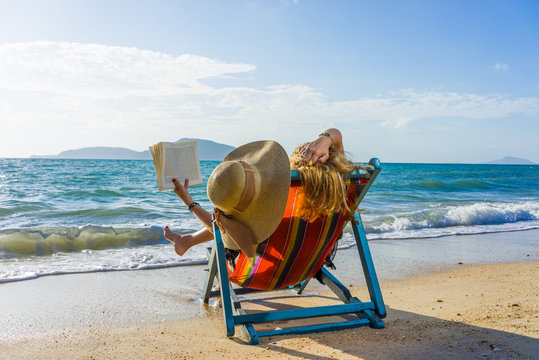 Young woman reading a book at the beach