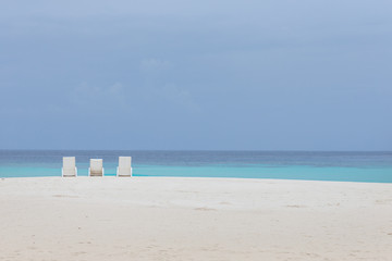 three chairs on the beach facing the blue sea