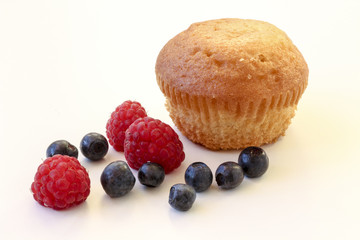 Beautiful homemade cake and raspberries with blueberries on a light background.