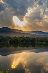 Fototapeta na wymiar Clouds and sunbeam over mountain and lake