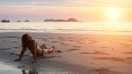 Young woman lying on the beach in the setting sun.