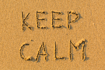 KEEP CALM - words hand-written on sand beach.