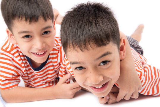 Little siblings boy brother smiling laying down together with happy face on white background