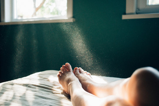 Sunlight streaming through window onto woman's legs on bed