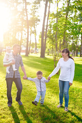 Fototapeta premium Happy young family with children walks in the summer park