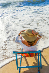 Young woman in hat sitting on beach