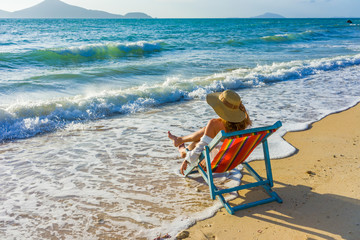 Fototapeta na wymiar Young woman in hat sitting on beach