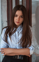 Beautiful girl standing near a window. The reflection in the window.