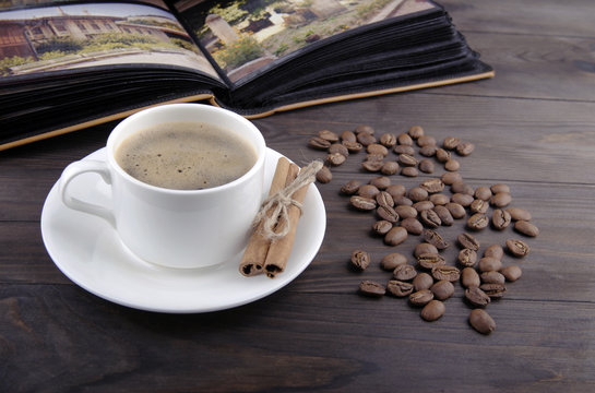 Coffee cup, beans and cinnamon on wood background