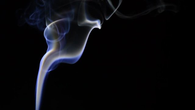 Column of smoke justify at left moving at wind on black background