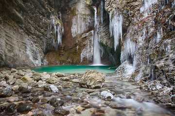 Fototapeta premium Frozen waterfall Kozjak in Slovenia with icicles and green water river pool .