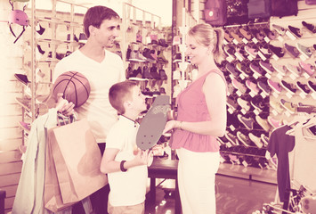 man and woman buying skateboard for son in sport shop