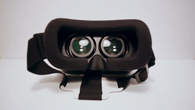 Virtual reality glasses for the smartphone on the white background, smartphone is working,mans hands take them and wear