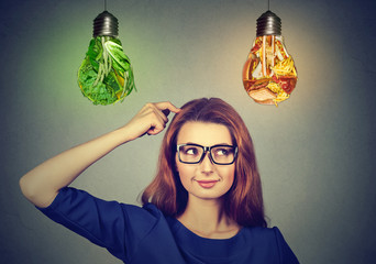 Woman thinking deciding on diet looking up at junk food vegetables light bulbs