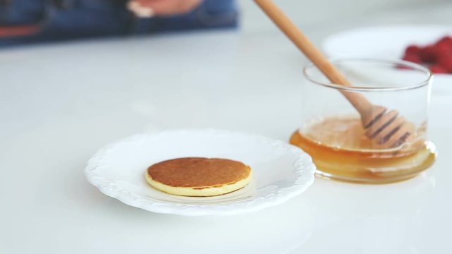 woman adds pancakes on white plate