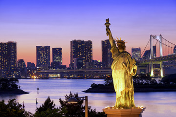Statue of Liberty and Rainbow bridge, located at Odaiba Tokyo, with Tokyo skyline in background at...