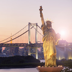 Statue of Liberty and Rainbow bridge, located at Odaiba Tokyo, with Tokyo skyline in background at twilight