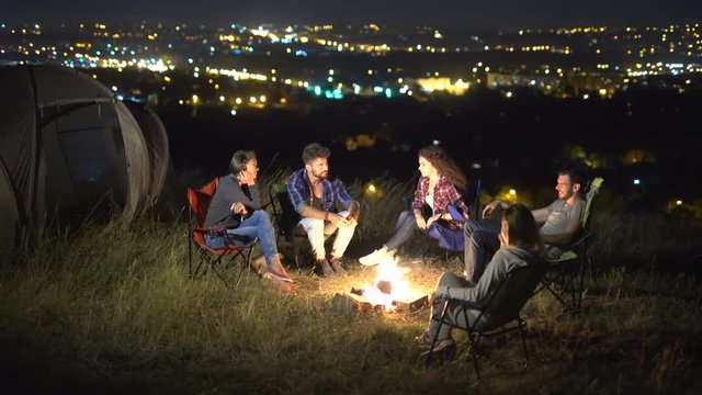 2 in 1 video! The people sit on the background of the city. Evening night time. Wide angle. Real time capture. Crane shot with camera pitch