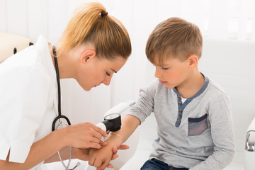 Doctor Examining Skin Of Little Boy