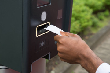 Close-up Of Person's Hand Inserting Ticket Into Parking Meter