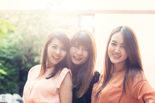 Three beautiful happy Asian girl smile and laugh together.Image with sunlight filter...