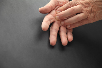 Senior man touches sore area of his hand.